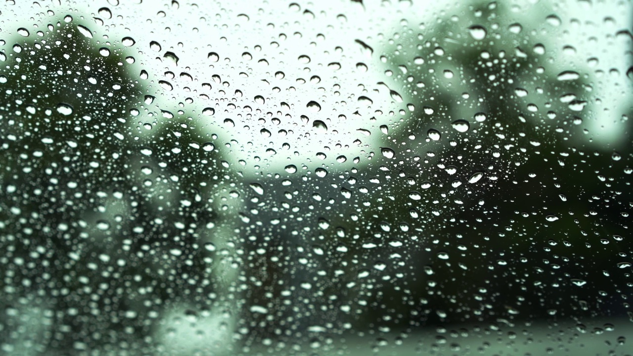 雨点和模糊离焦灯后面的雨点在草车。视频素材