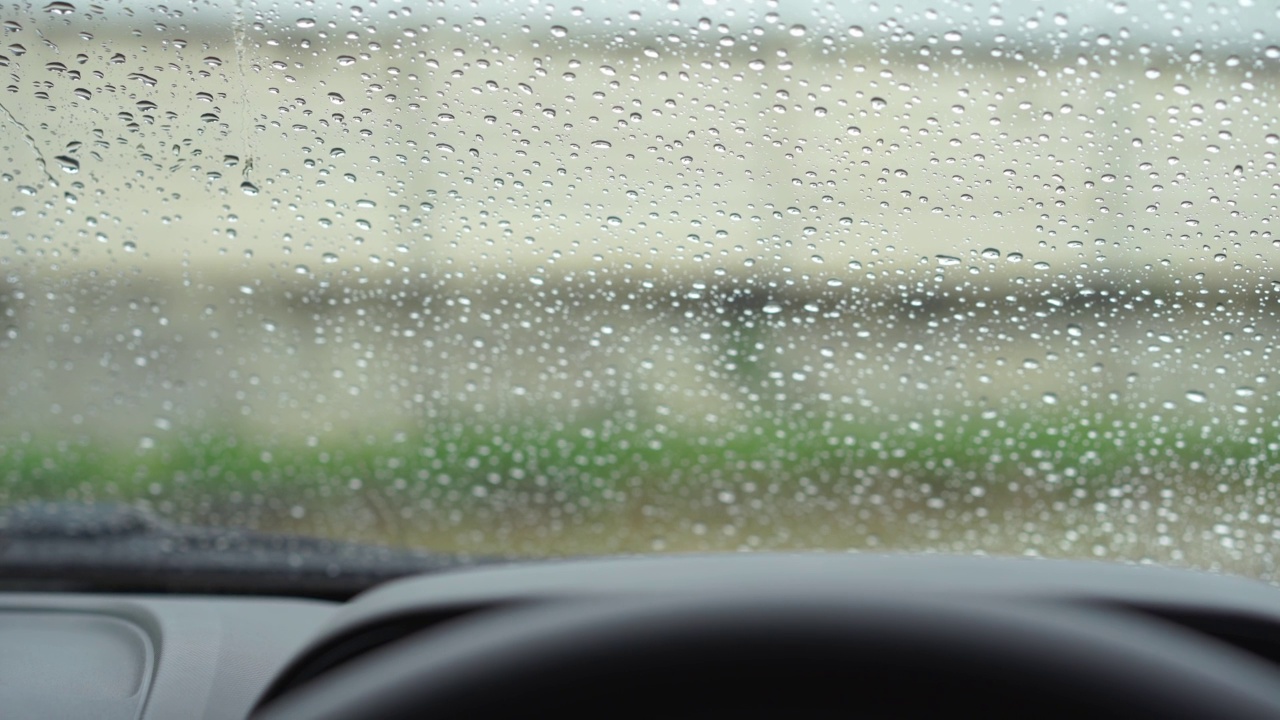 雨点和模糊离焦灯后面的雨点在草车。视频素材