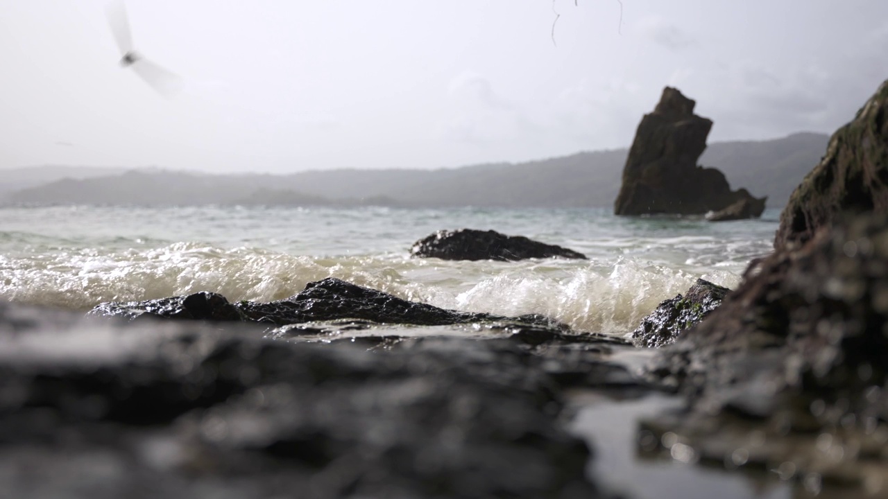 特写的岩石海岸，波纹的水面和大海中的一个大石头作为背景视频素材