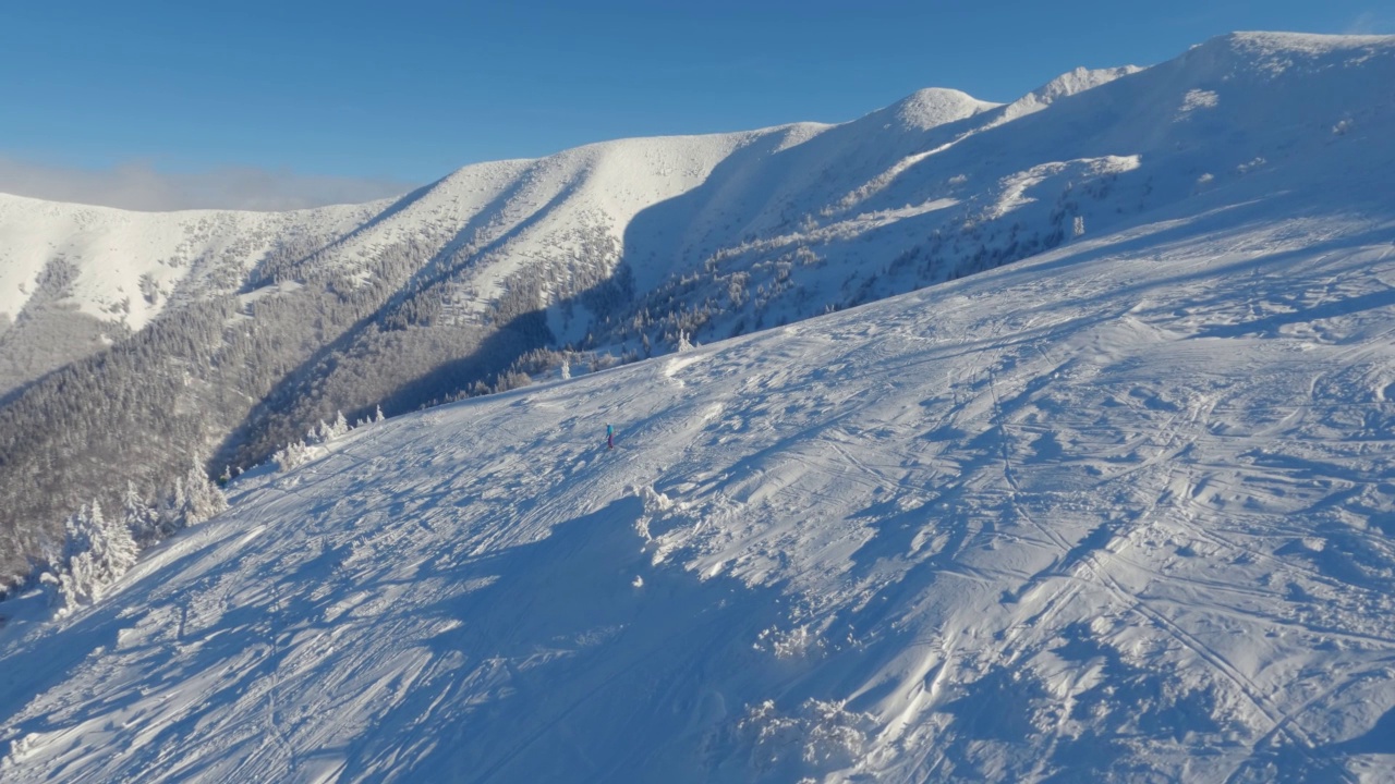 雪山自然中，冬季阳光明媚的早晨，空空如也的滑雪场鸟瞰图，山坡上有新鲜的雪视频素材