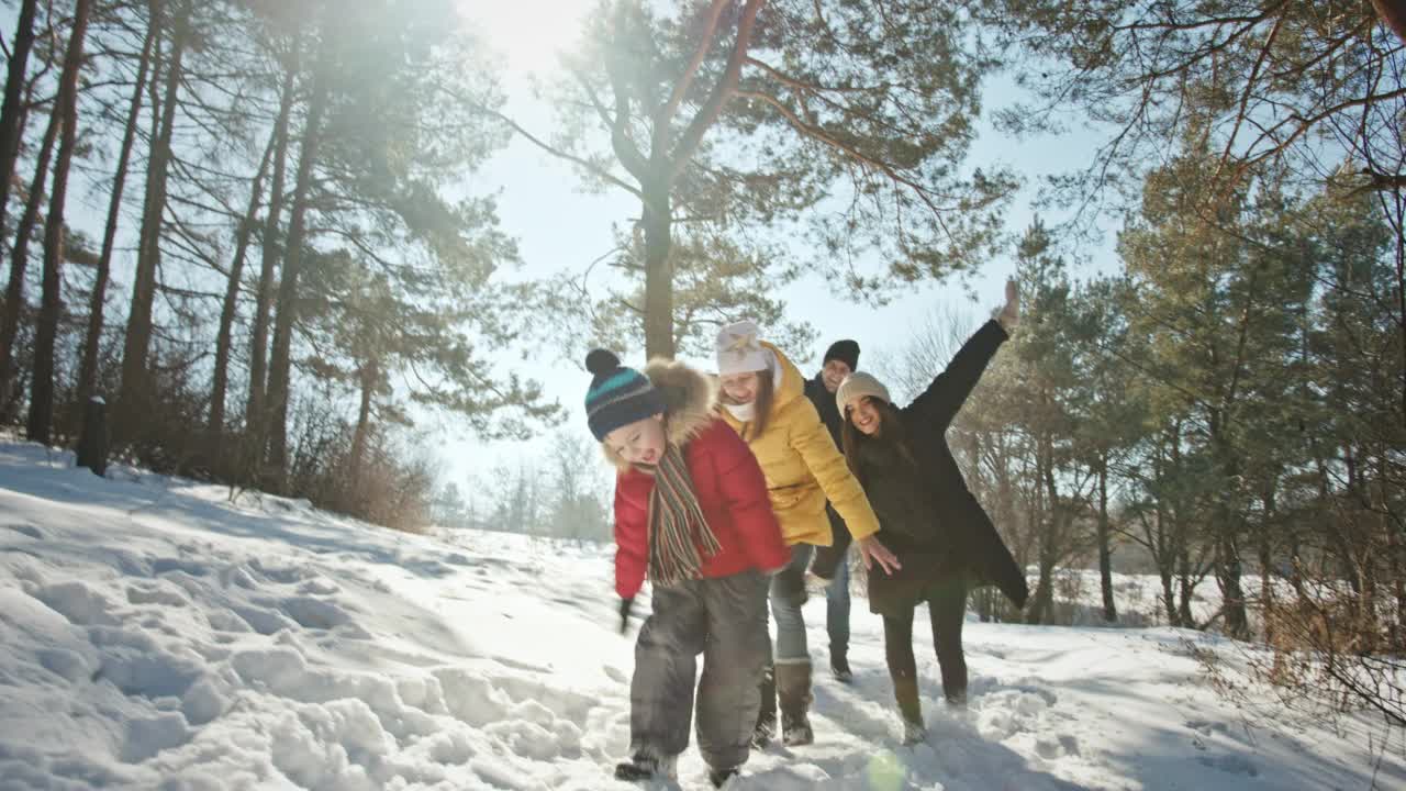 父母和孩子在森林里沿着雪道玩耍视频素材