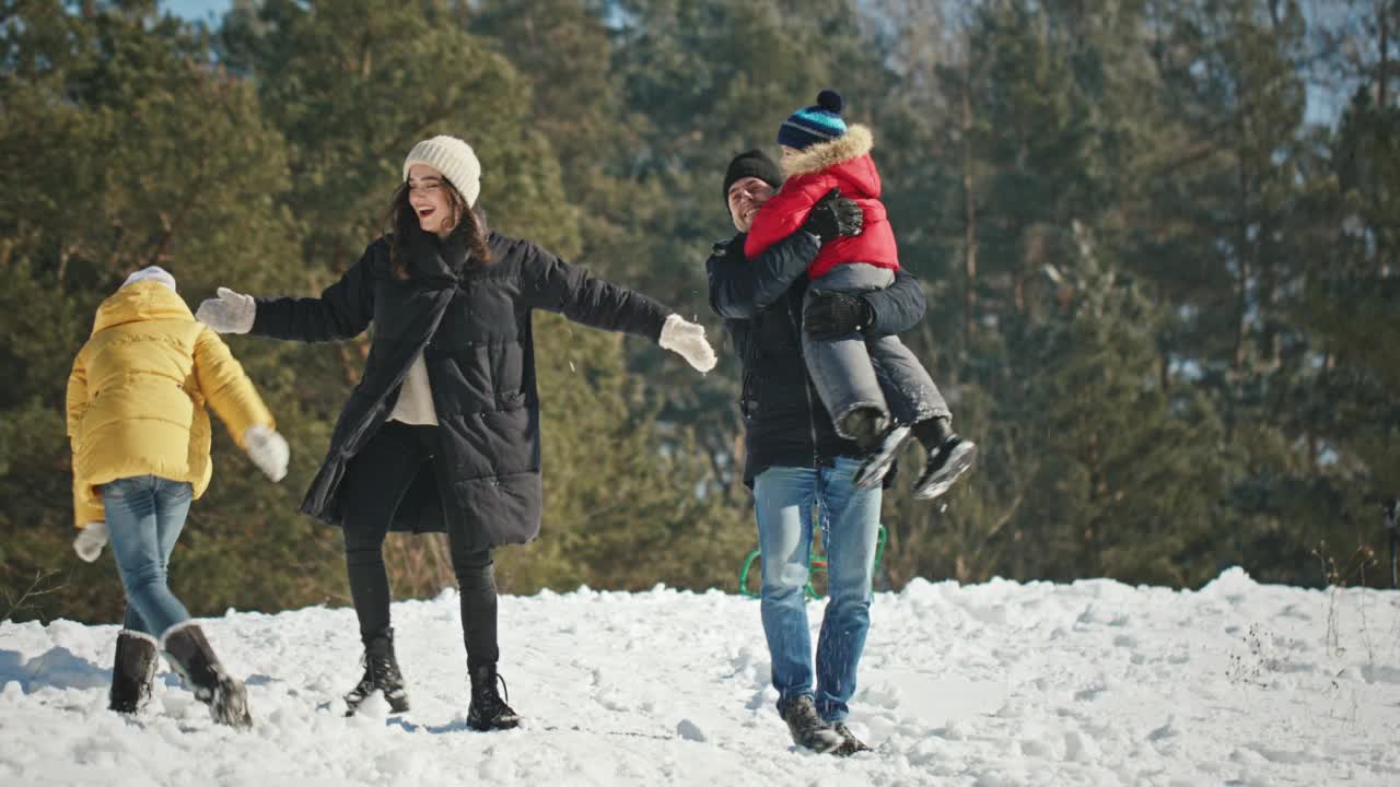 他们玩雪球。一个中年男子和一个5岁的孩子在堆雪人。和家人一起享受快乐和幸福。视频素材