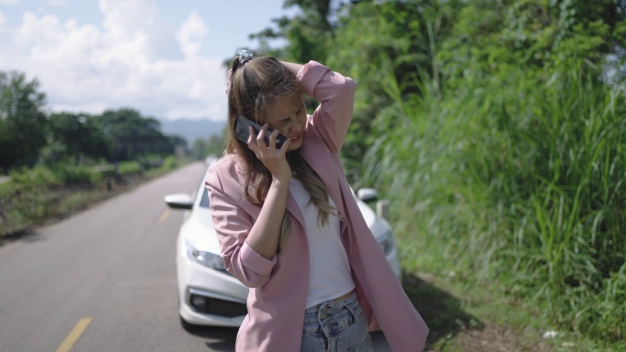 年轻女子有一个问题，汽车故障和使用手机服务在道路上视频素材