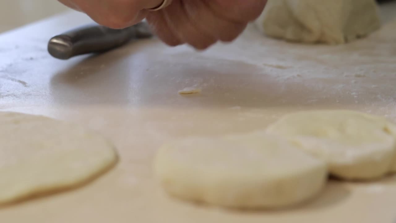 一个女人在家里做馅饼。在家做饭和烘焙。为烘焙准备面团。检验批。一名妇女在家庭厨房里准备炸酵母面团派。手工制作食物的概念。视频素材