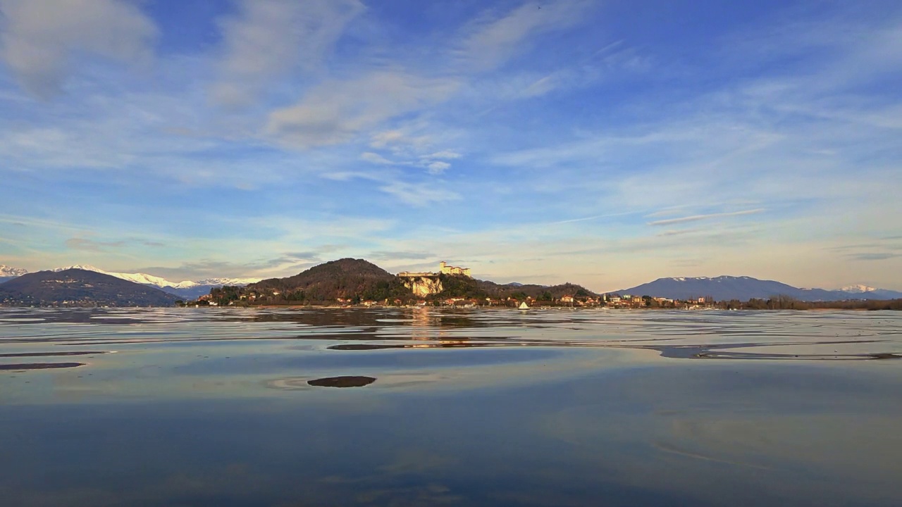 令人惊叹的优雅的白天鹅在湖面上游泳，城堡为背景，山与雪在日落。低角度表面水平视频素材