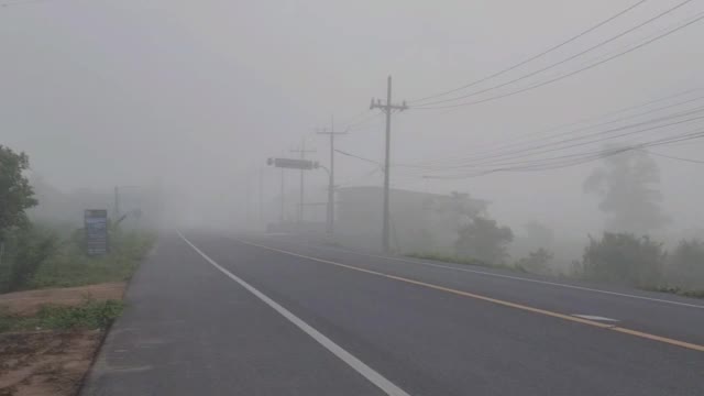 早晨，一辆小货车驶过一条浓雾弥漫的道路。视频下载