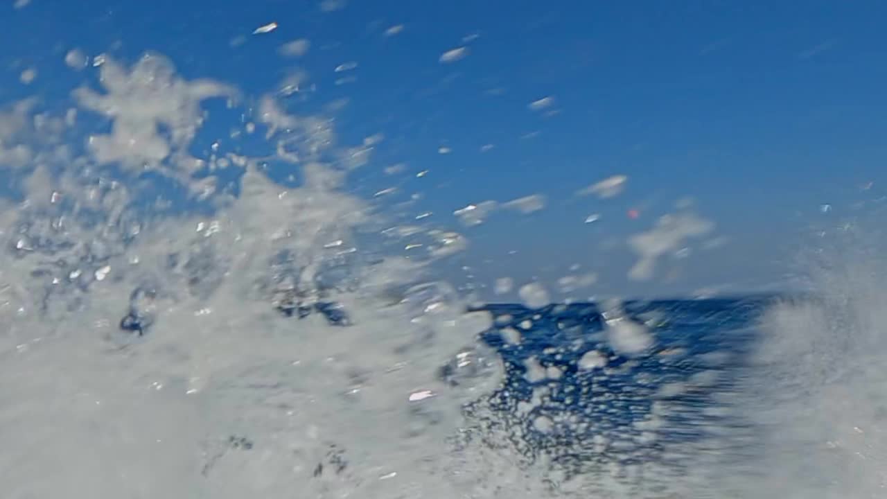 摩托艇上的乘客在海水中快速航行，扬起水花。慢动作视频素材