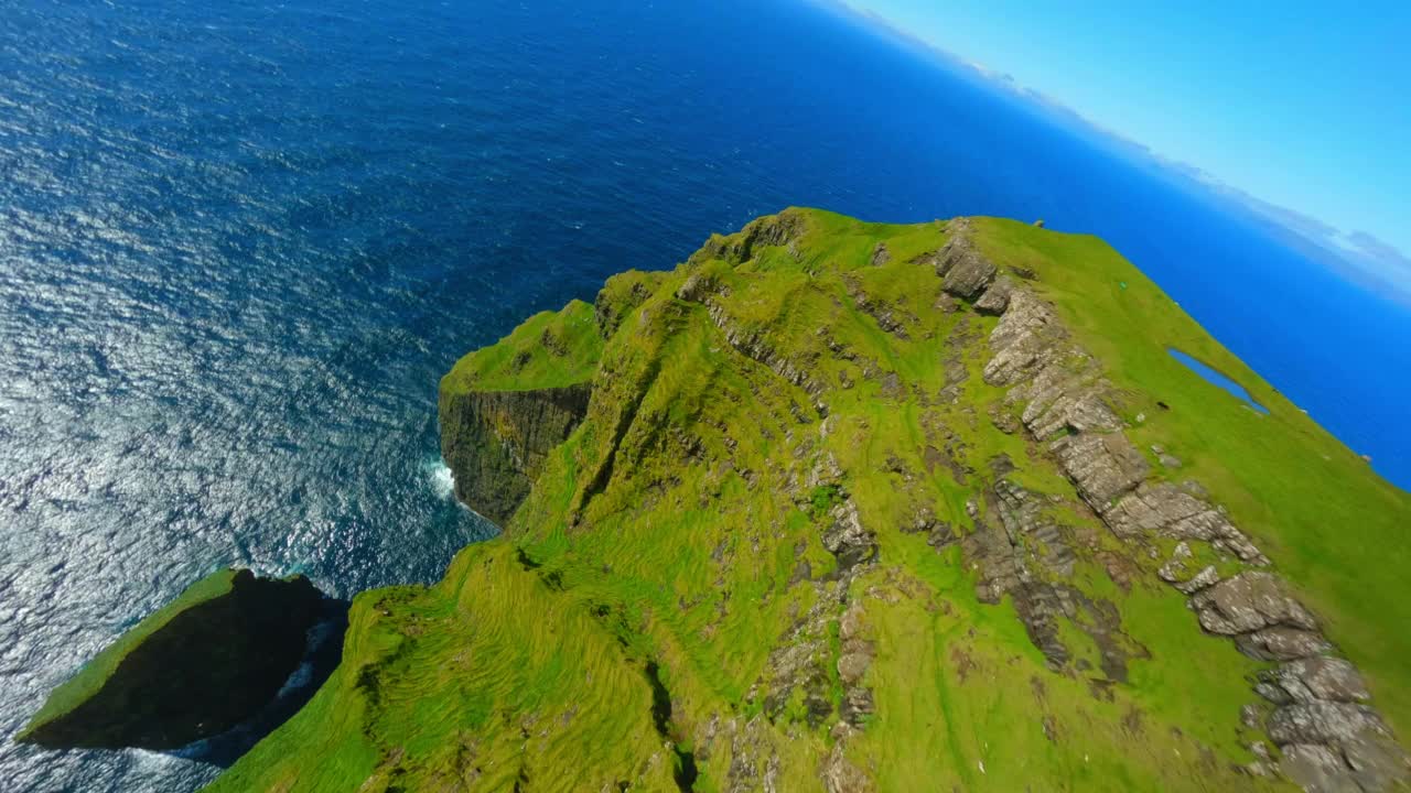 在阳光明媚的日子里，空中向下拍摄海洋中岩石上生长的植物-丹麦法罗群岛视频素材