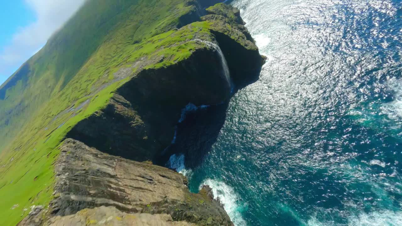 空中倾斜的风景拍摄瀑布在海上流动，无人机向前飞越岛屿景观-法罗群岛，丹麦视频素材