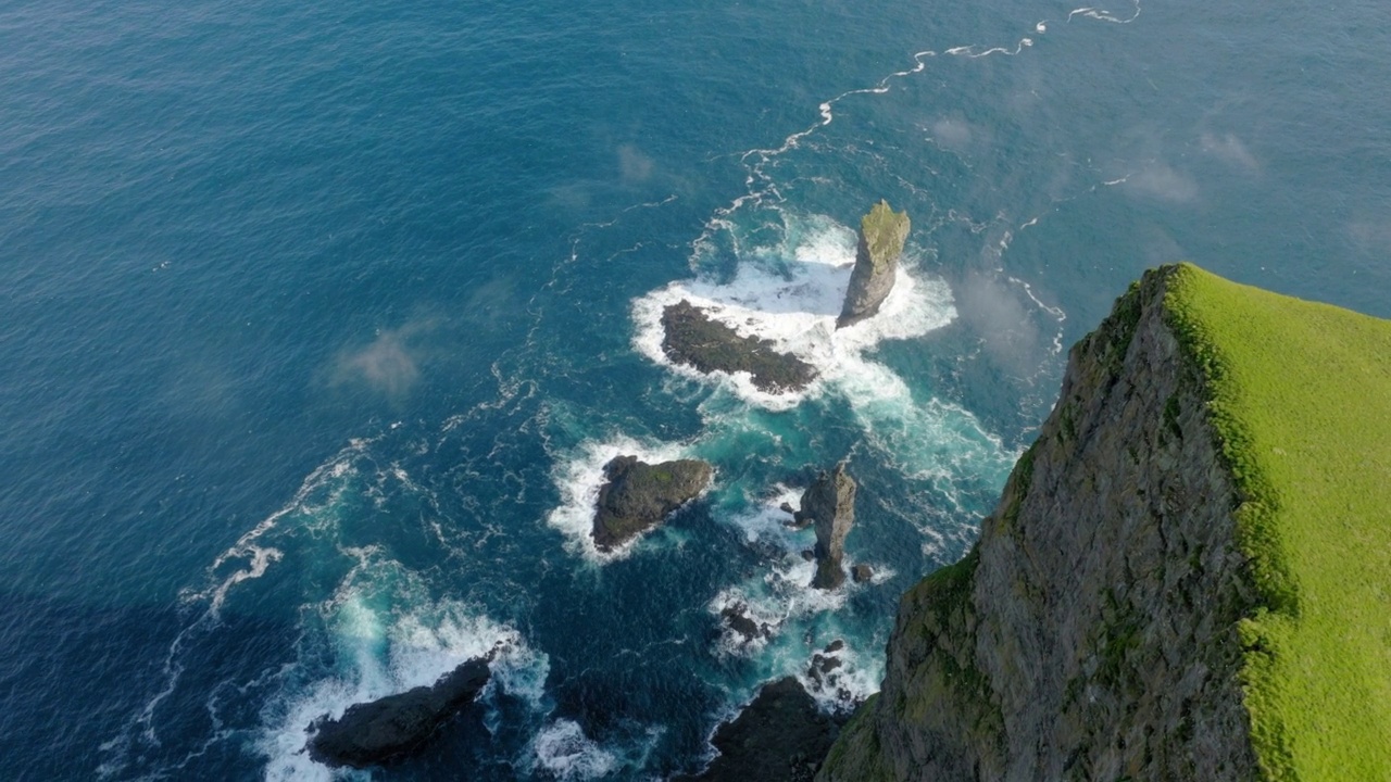 空中拍摄海浪中的岩石美景，无人机在阳光明媚的日子飞行-丹麦法罗群岛视频素材