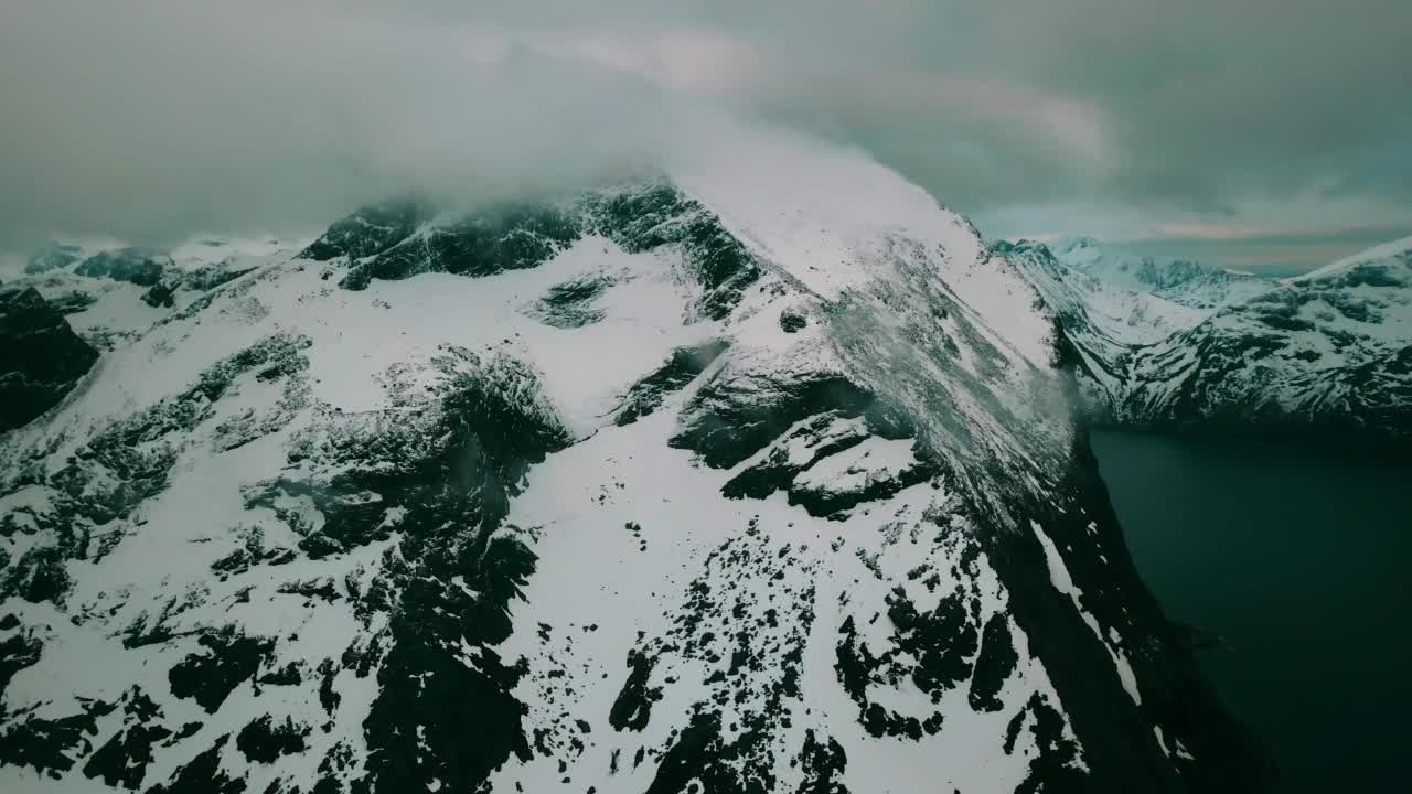 空中向前拍摄的云下宁静山脉上的雪——挪威特罗姆瑟视频素材