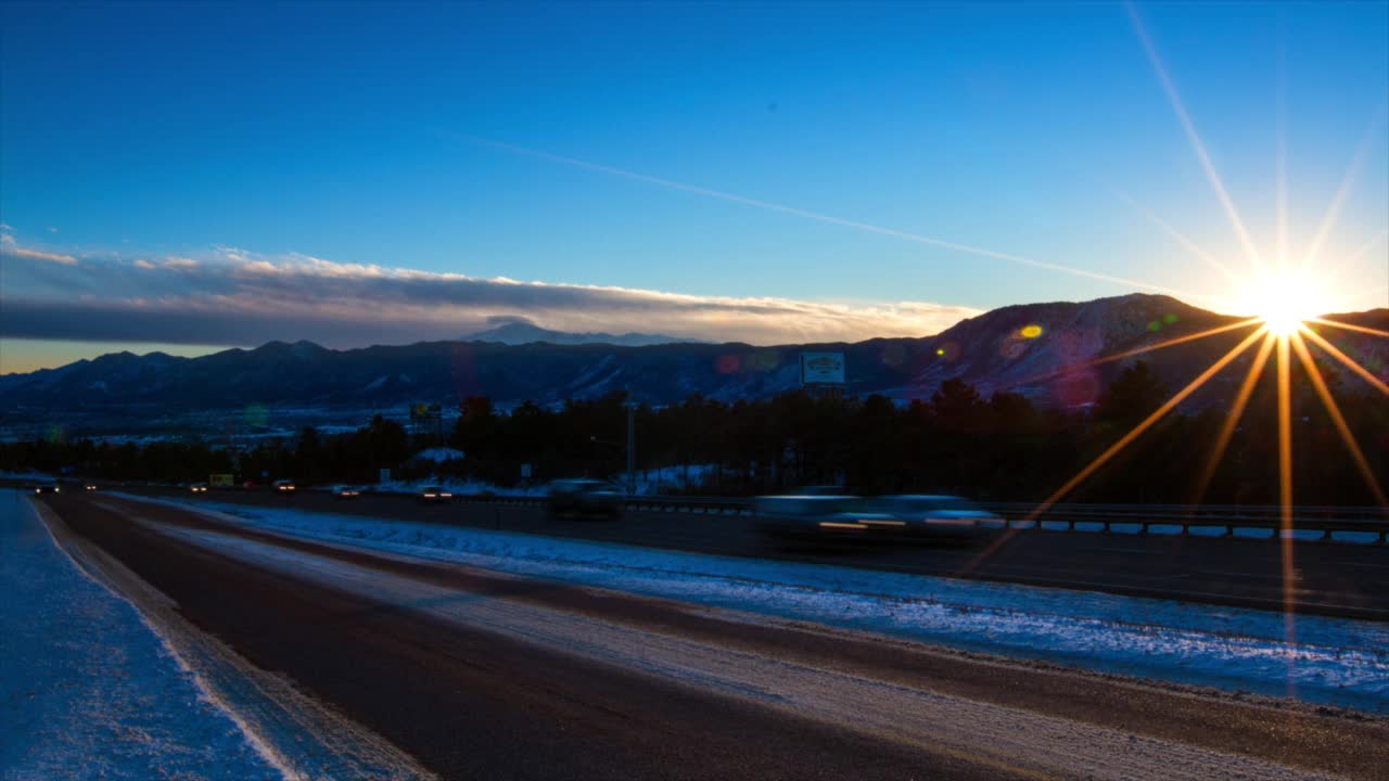 日落时分，在雪山边公路上行驶的车辆的长时间曝光延时锁定镜头——科罗拉多州布雷肯里奇视频素材