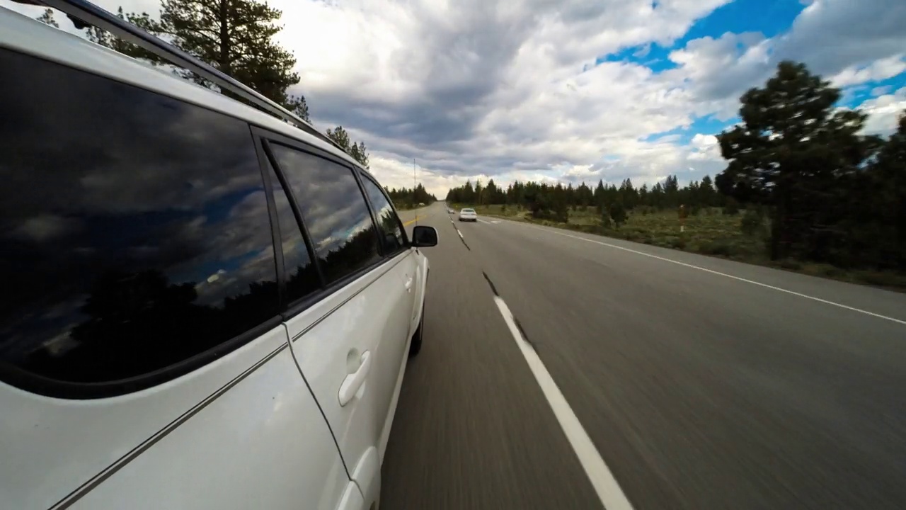 从汽车在多云天空下森林中的道路上移动的时间推移视角-约塞米蒂，加利福尼亚州视频素材