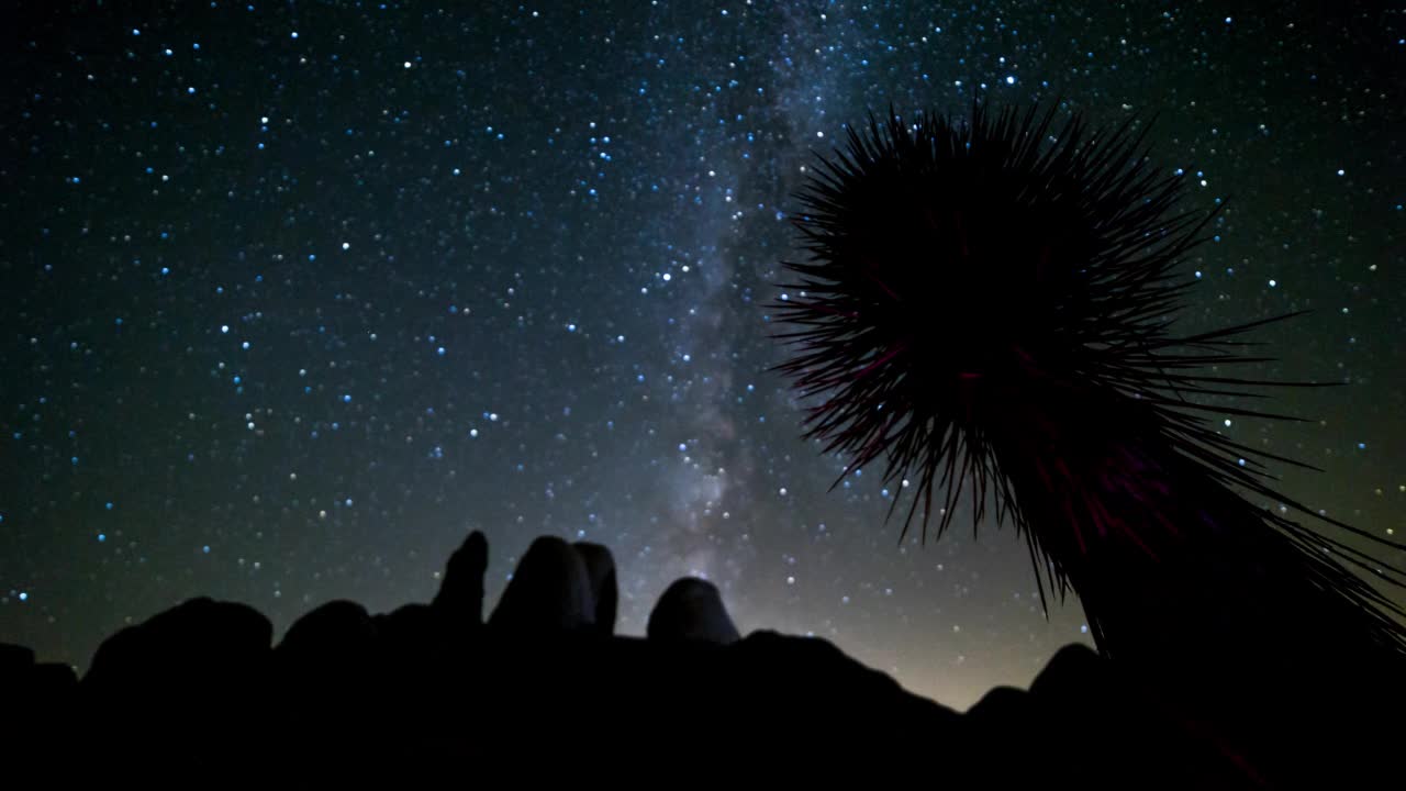 时间推移拍的剪影发光的星星移动在岩石在夜间-约书亚树，加利福尼亚视频素材