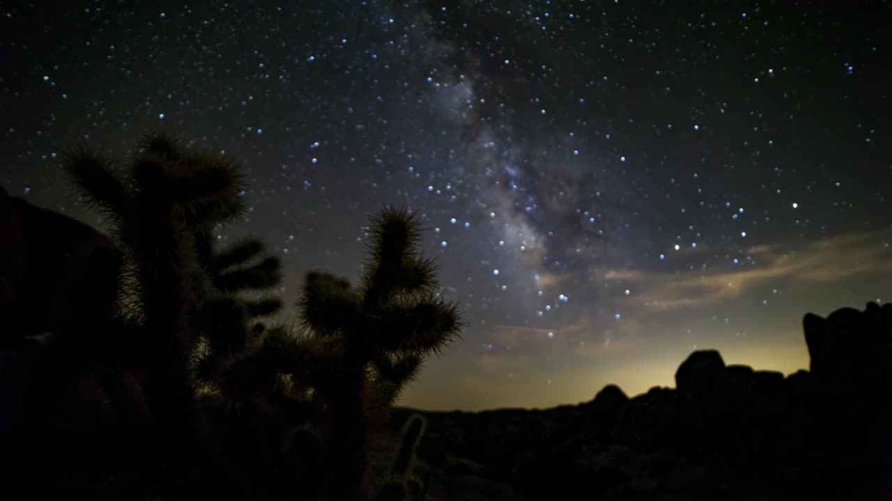 夜间约书亚树国家公园，闪烁的星星在岩石上移动的时间推移平移镜头视频素材