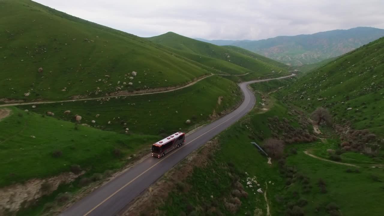 空中拍摄的豪华房车在路上行驶，无人机向后上升越过绿色山脉-贝克斯菲尔德，加利福尼亚州视频素材