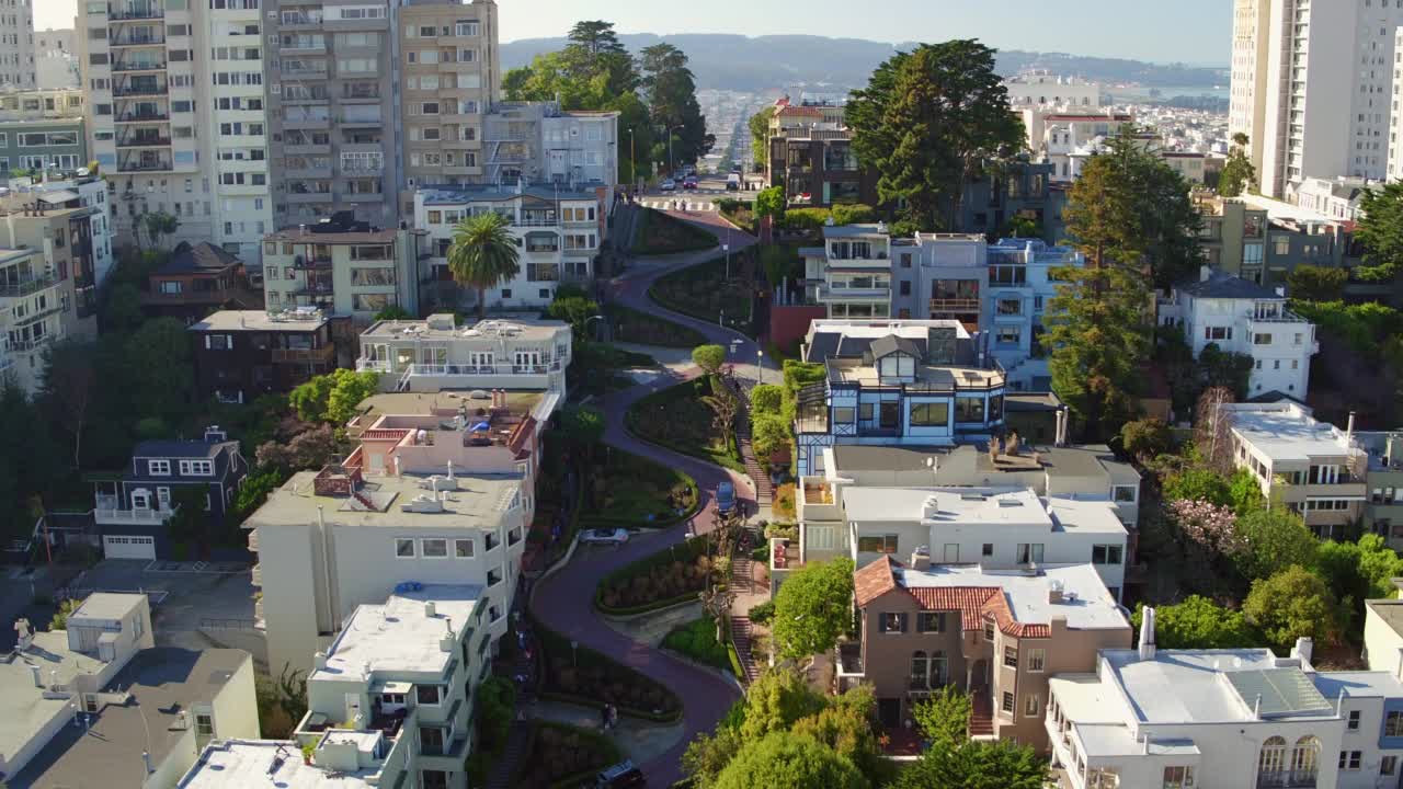 空中拍摄的城市建筑中弯曲的道路，无人机在阳光明媚的日子向后飞行-旧金山，加利福尼亚州视频素材