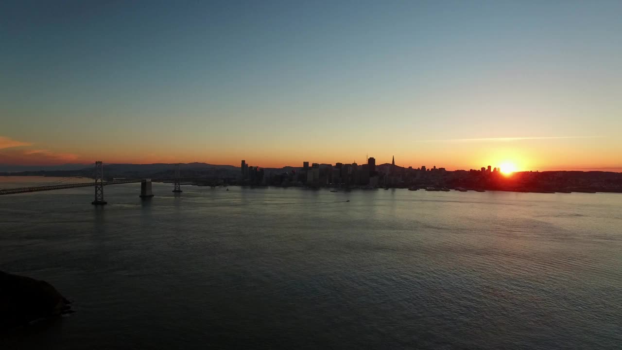 城市悬索桥的鸟瞰图，无人机在夕阳下掠过波光粼粼的海面——旧金山，加利福尼亚视频素材