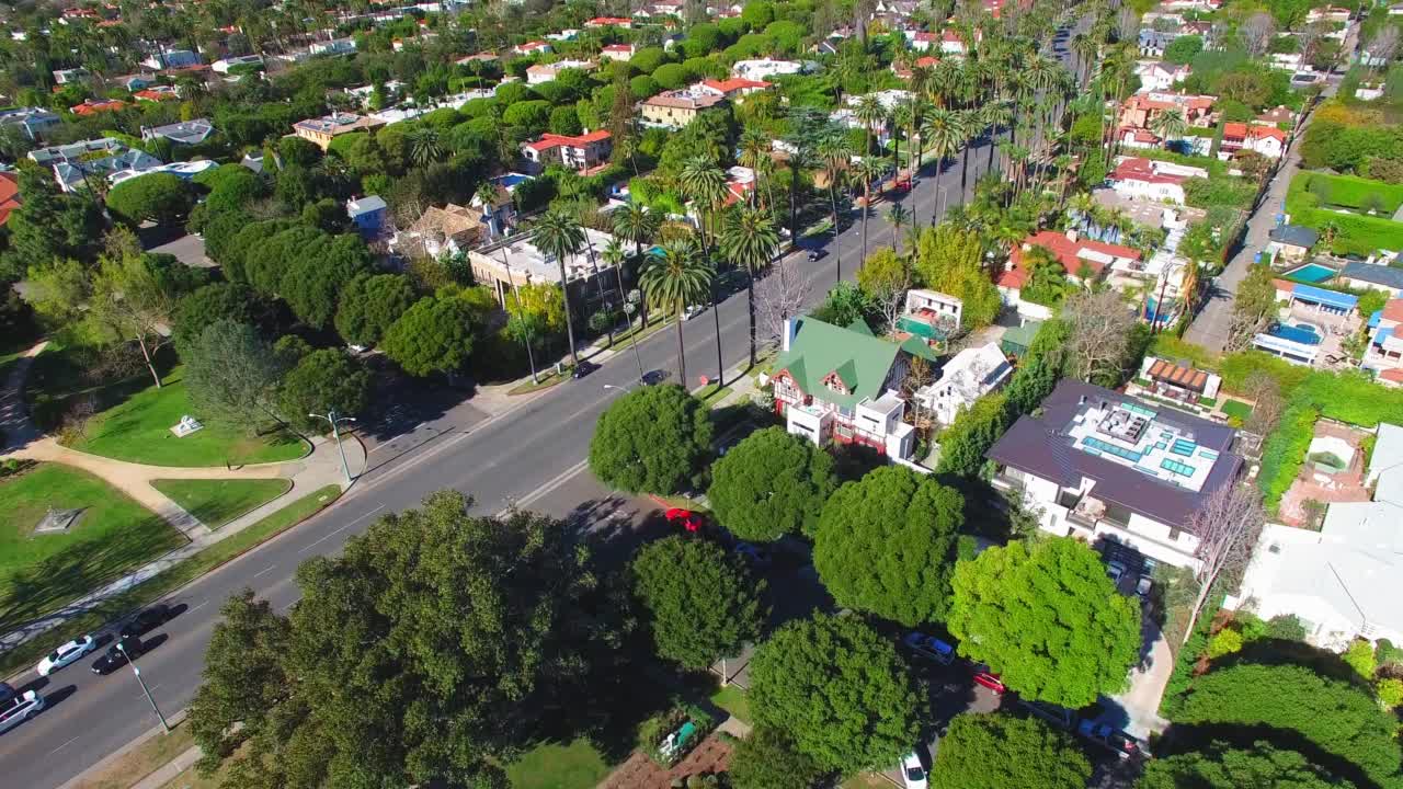 空中拍摄的住宅在城市的绿树中，无人机在阳光明媚的日子向前飞行-比弗利山，加利福尼亚州视频素材