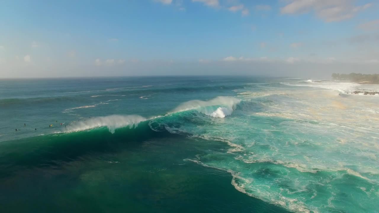 从空中向下拍摄的游客在度假时带着冲浪板漂浮在海浪中——夏威夷的瓦胡岛视频素材