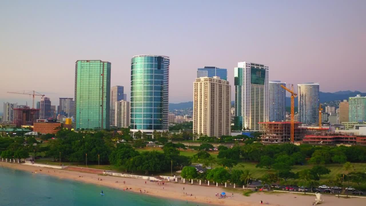 航拍:航拍的人们在现代城市的海滩，无人机向后飞海-瓦胡岛，夏威夷视频素材