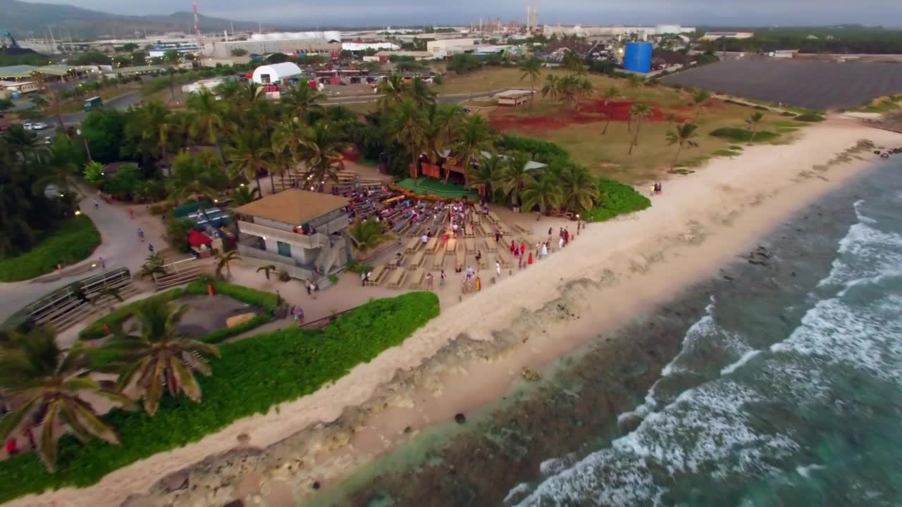 航拍:航拍瓦胡岛海滩上的游客，无人机在海面上向后飞行视频素材