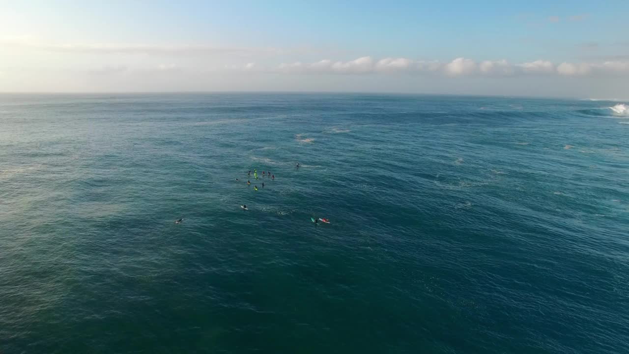 空中封锁拍摄的游客带着冲浪板在多云的天空下的海浪中——夏威夷瓦胡岛视频素材