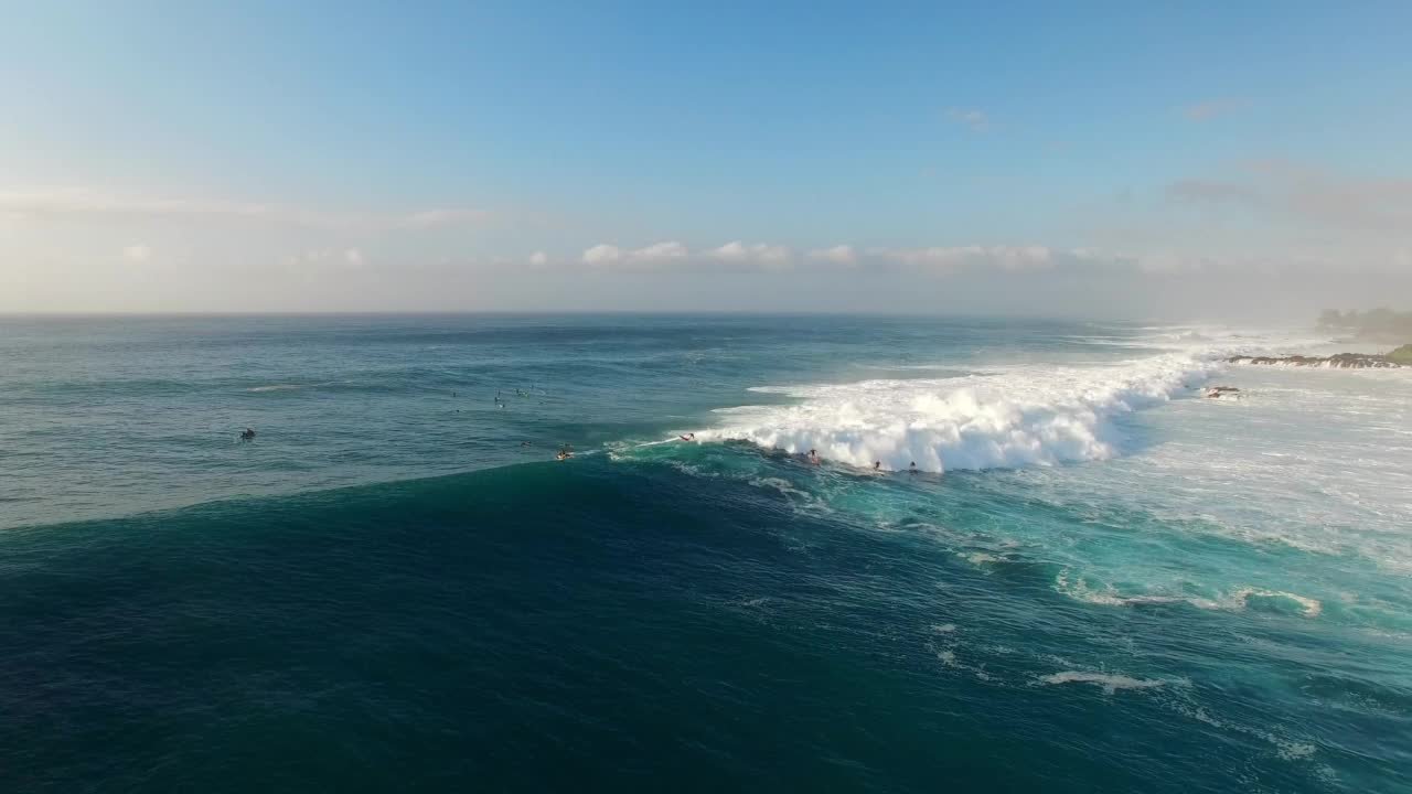 航拍:航拍人们用冲浪板在波浪般的海洋上游泳，无人机在阳光明媚的日子向前飞行——夏威夷瓦胡岛视频素材