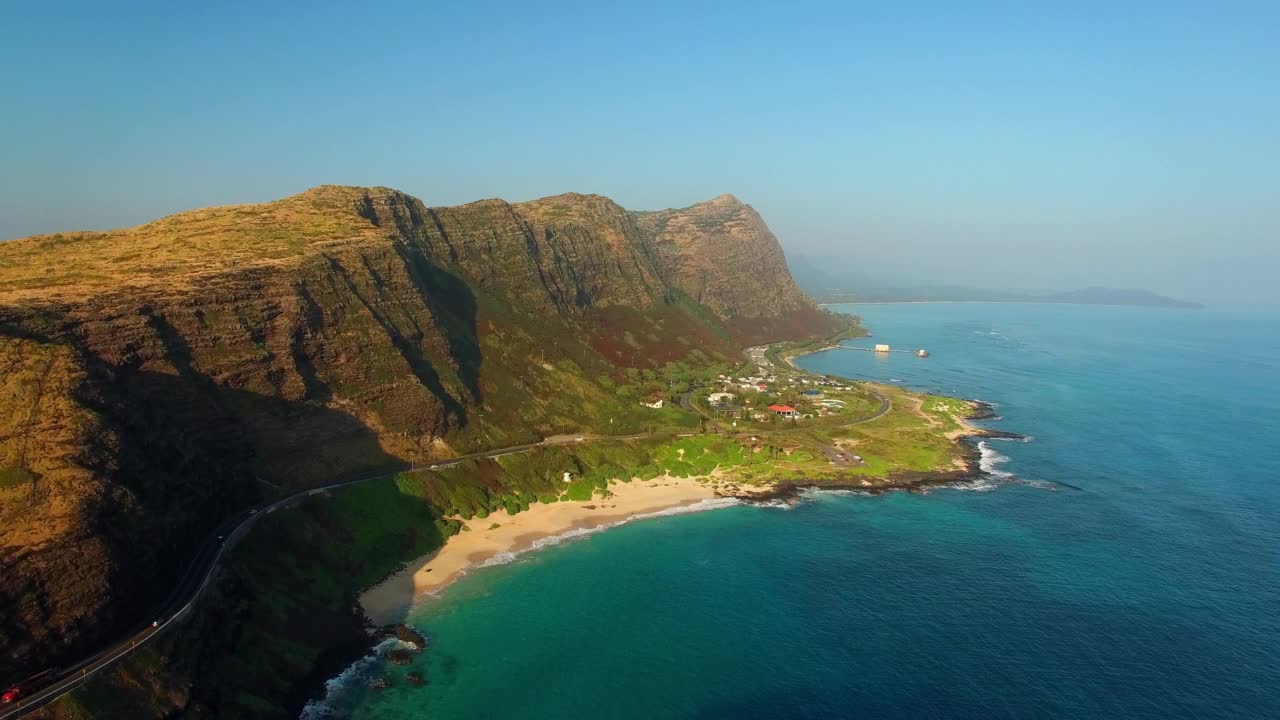 天空晴朗的天空下，在大海和山脉之间的绿色岛屿上，空中拍摄美丽的建筑景观-夏威夷瓦胡岛视频素材