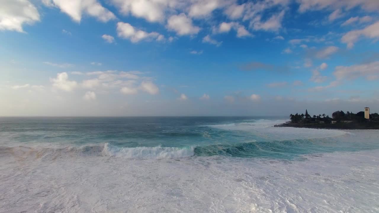 空中向前拍摄的人们带着冲浪板在波浪海上的岛屿在天空的云下-瓦胡岛，夏威夷视频素材