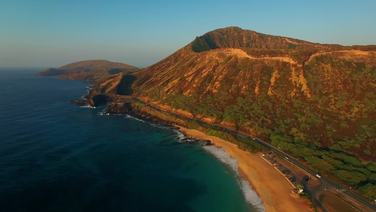 航拍:航拍在瓦胡岛行驶的汽车。无人机在海滩上空向后飞行视频素材