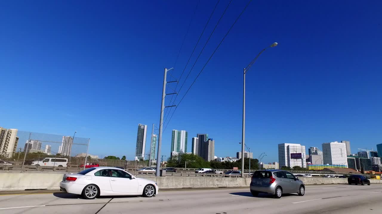 在晴朗的天空下，汽车在现代城市的道路上移动的观点-迈阿密，佛罗里达州视频素材