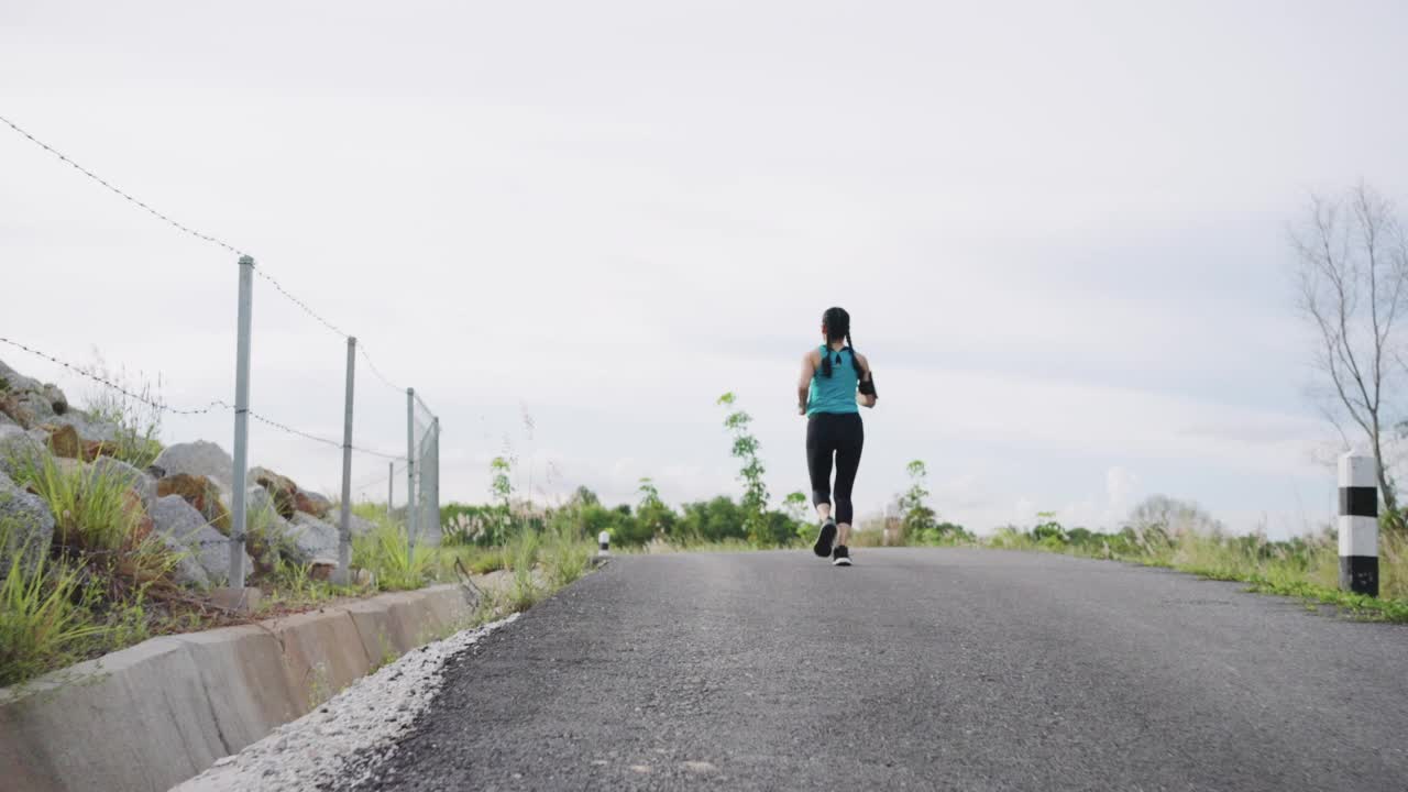 一个年轻女子跑过一个小水库的慢镜头视频素材