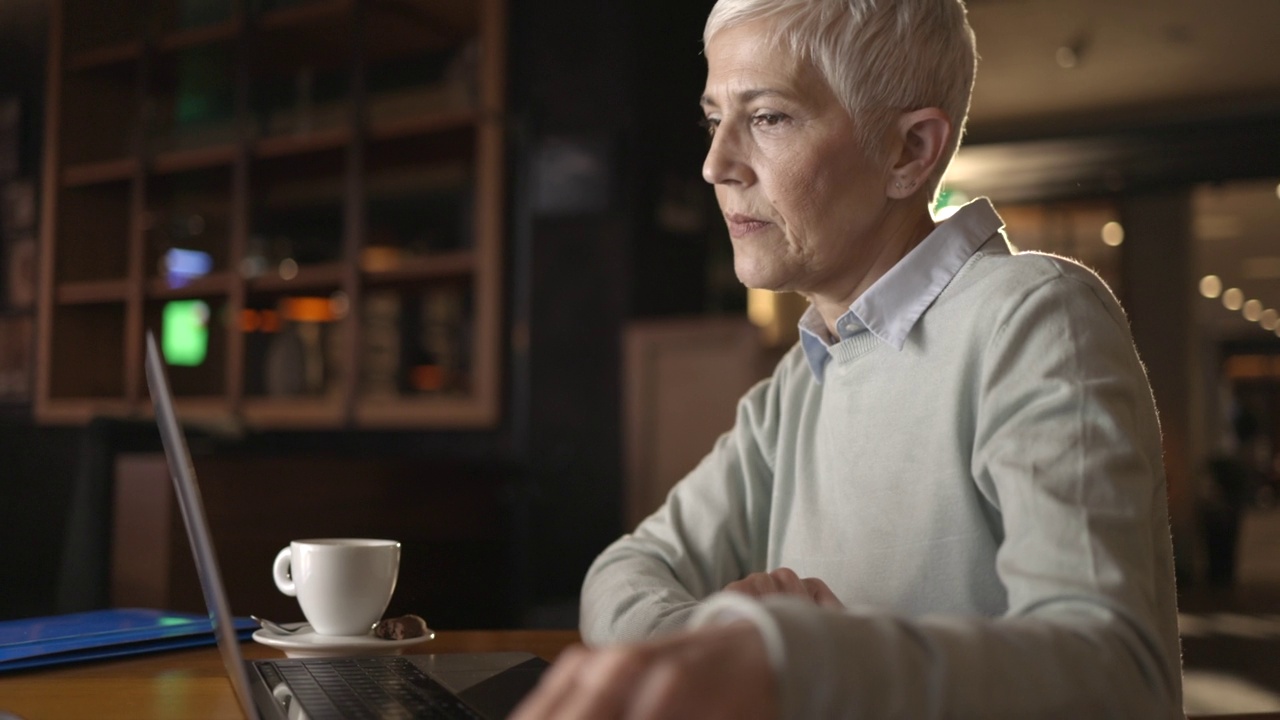 成熟的女商人在café的笔记本电脑上工作。视频素材