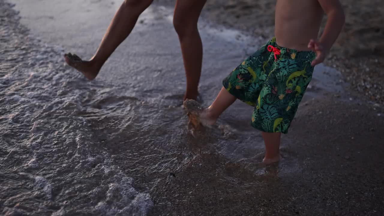 母子俩在公共海滩上用脚挖沙子视频素材