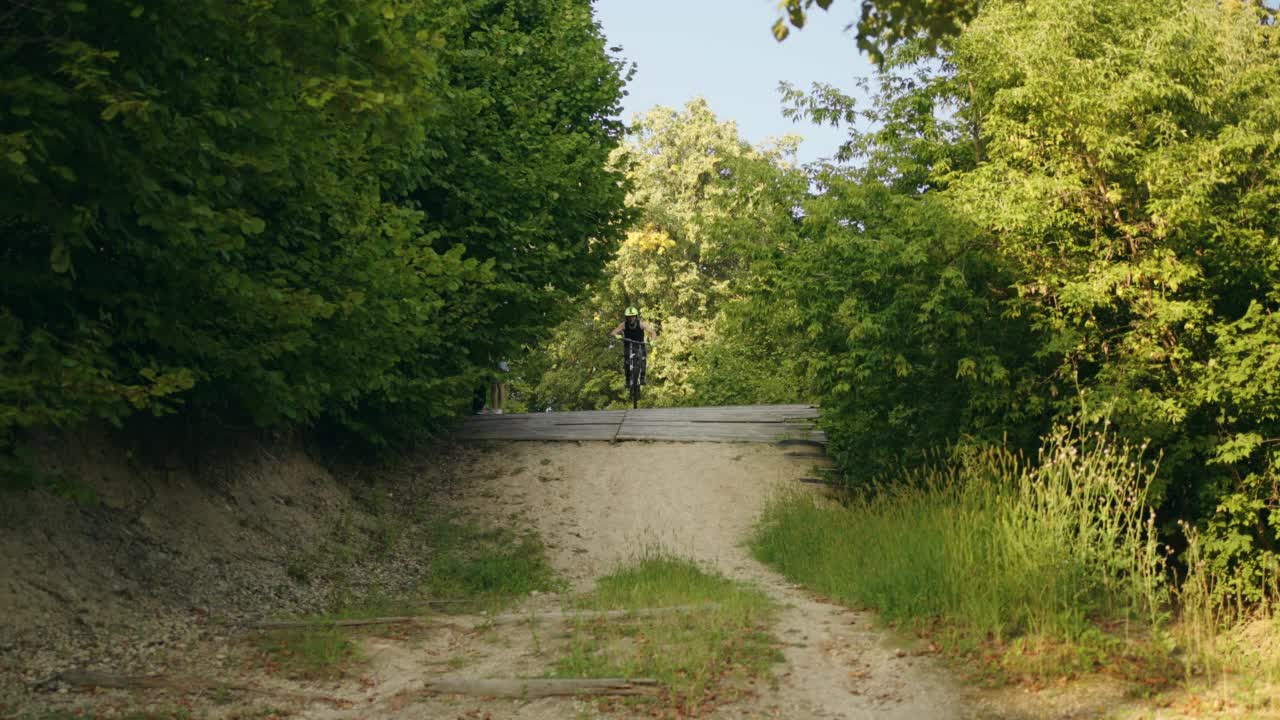 森林道路自行车上的极限技巧，年轻的运动男子骑MTB自行车在林地，慢动作视频素材