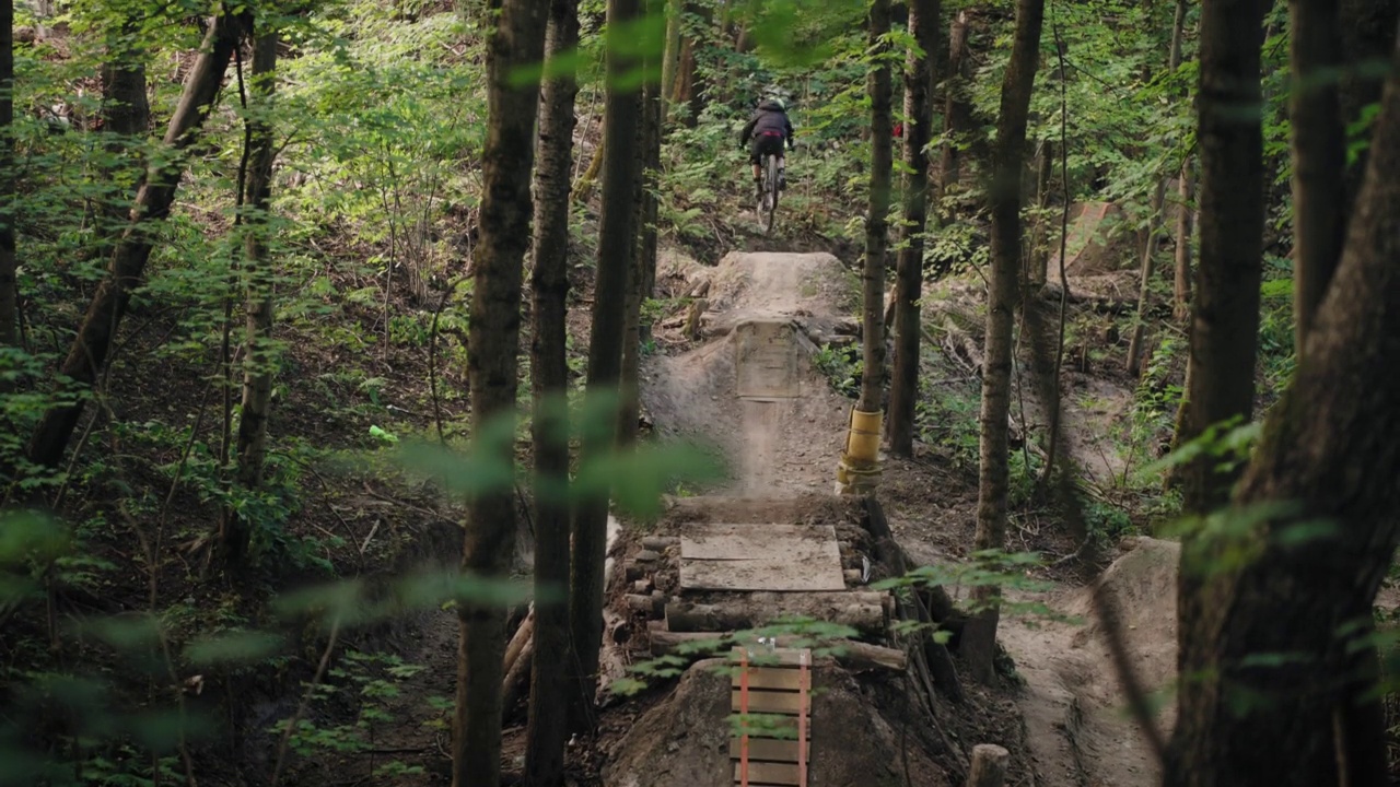 电影镜头森林自行车骑山地车加速和跳上跳板视频素材