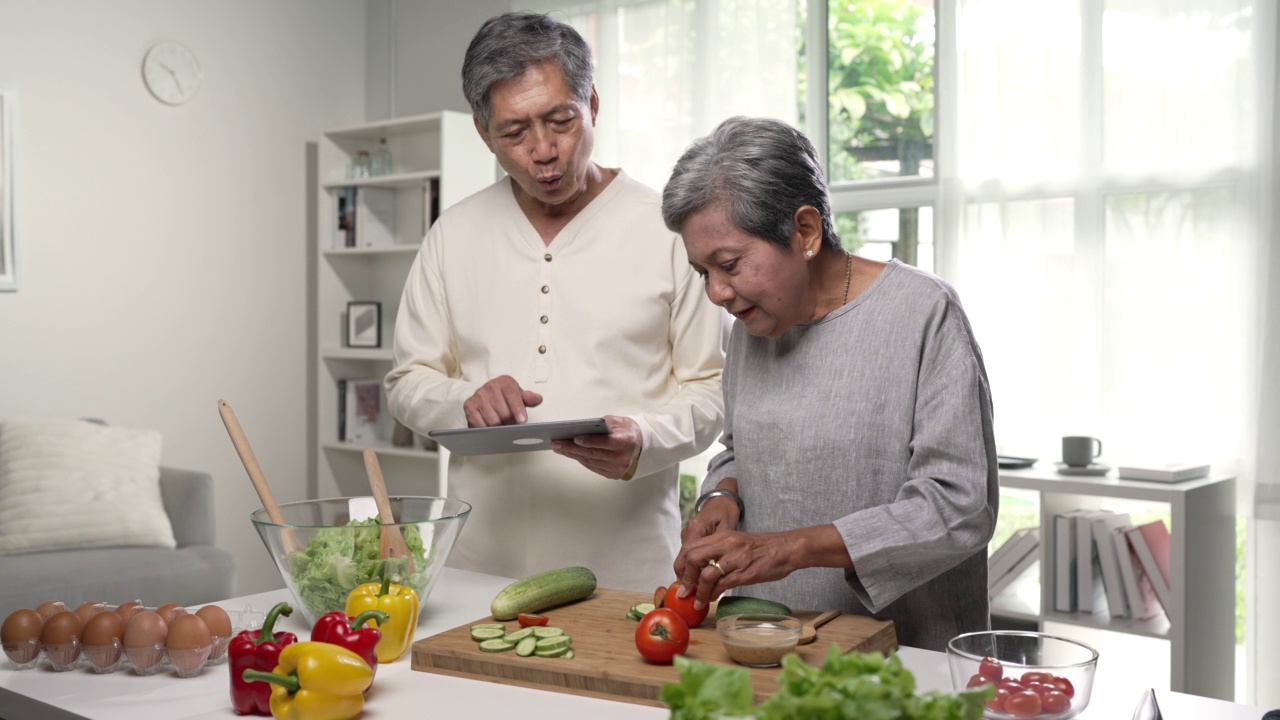 快乐的亚洲老夫妇在他们的厨房里享受和准备健康的食物。视频素材