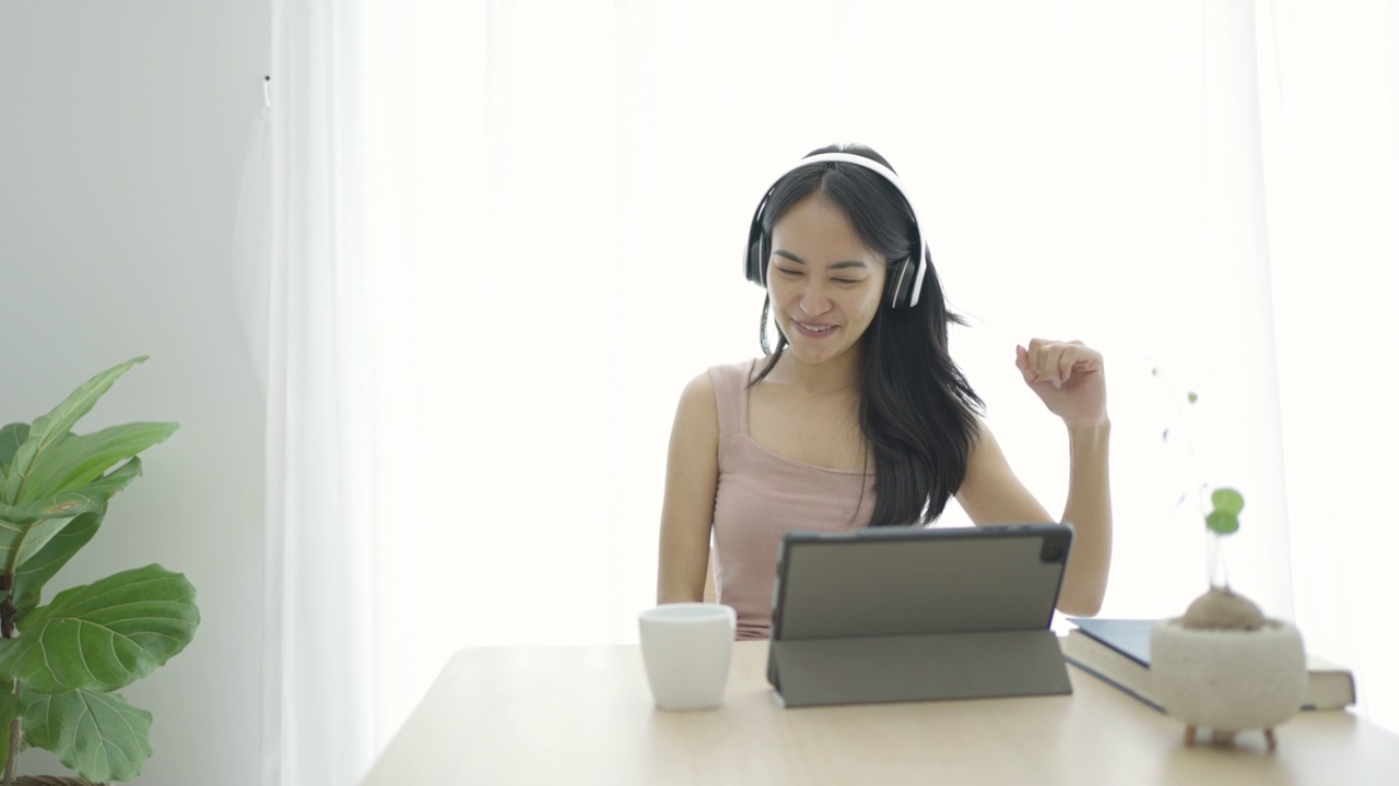 年轻的亚洲女子放松在沙发和听音乐与耳机在客厅在家里视频素材