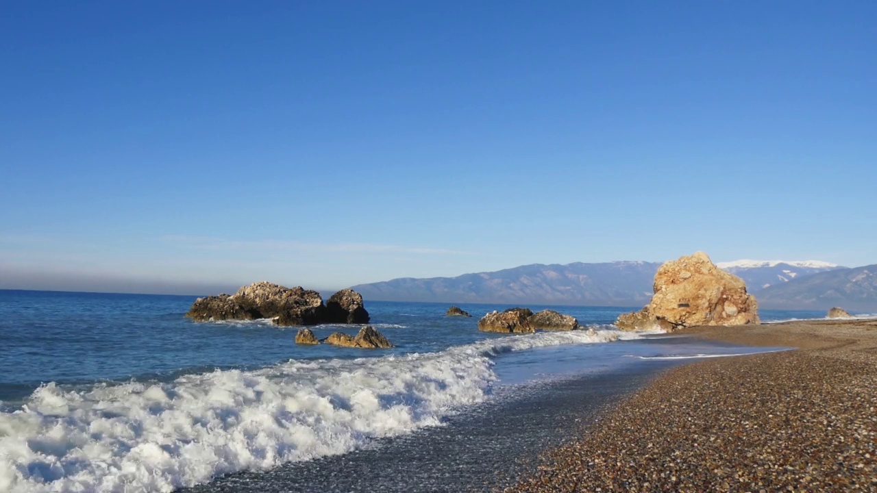 宁静的海景，岸边有岩石，早晨的阳光照亮了平静的海浪视频素材