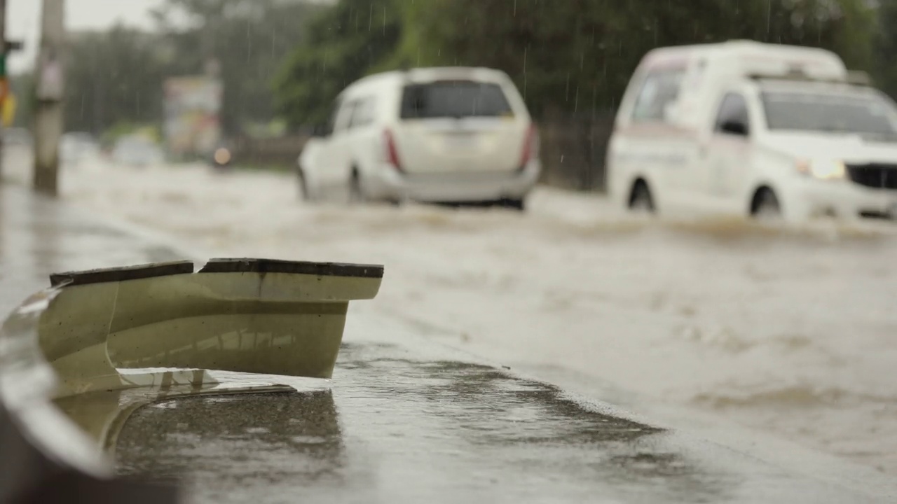 在暴雨引发的洪水中行驶在被淹道路上的汽车。雨下着，汽车跑在满是水的路上。视频素材