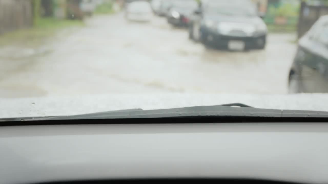 在暴雨引发的洪水中行驶在被淹道路上的汽车。从车内看。视频素材