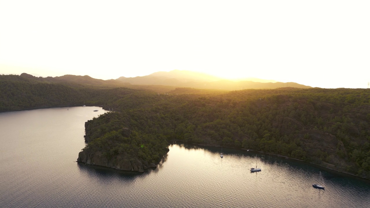 一个海湾和船停泊在爱琴海的海岸日落，美丽的海湾和岛屿在地中海附近Göcek在土耳其，空中帆船白帆在开放的大海，蓝色的水，每日船游，蓝色的航行视频素材