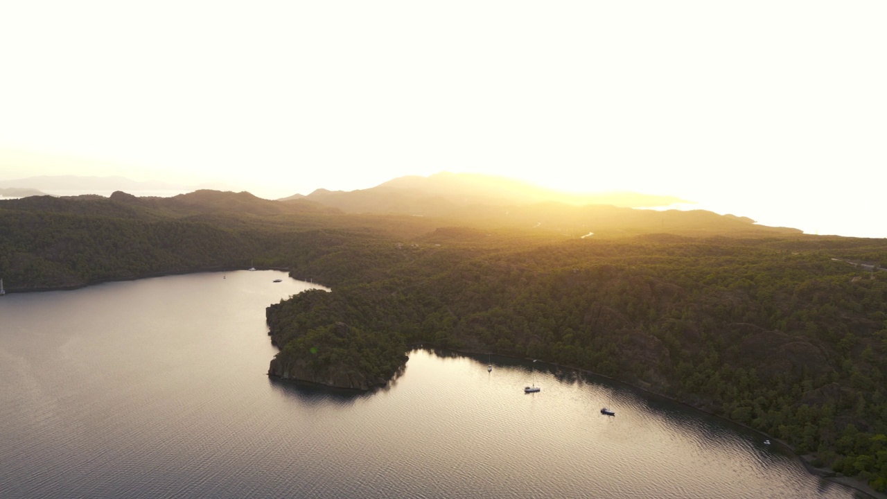 一个海湾和船停泊在爱琴海的海岸日落，美丽的海湾和岛屿在地中海附近Göcek在土耳其，空中帆船白帆在开放的大海，蓝色的水，每日船游，蓝色的航行视频素材