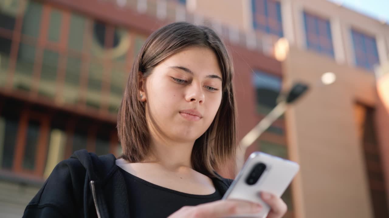 少年拿着手机在外面。女孩在户外打电话。视频素材