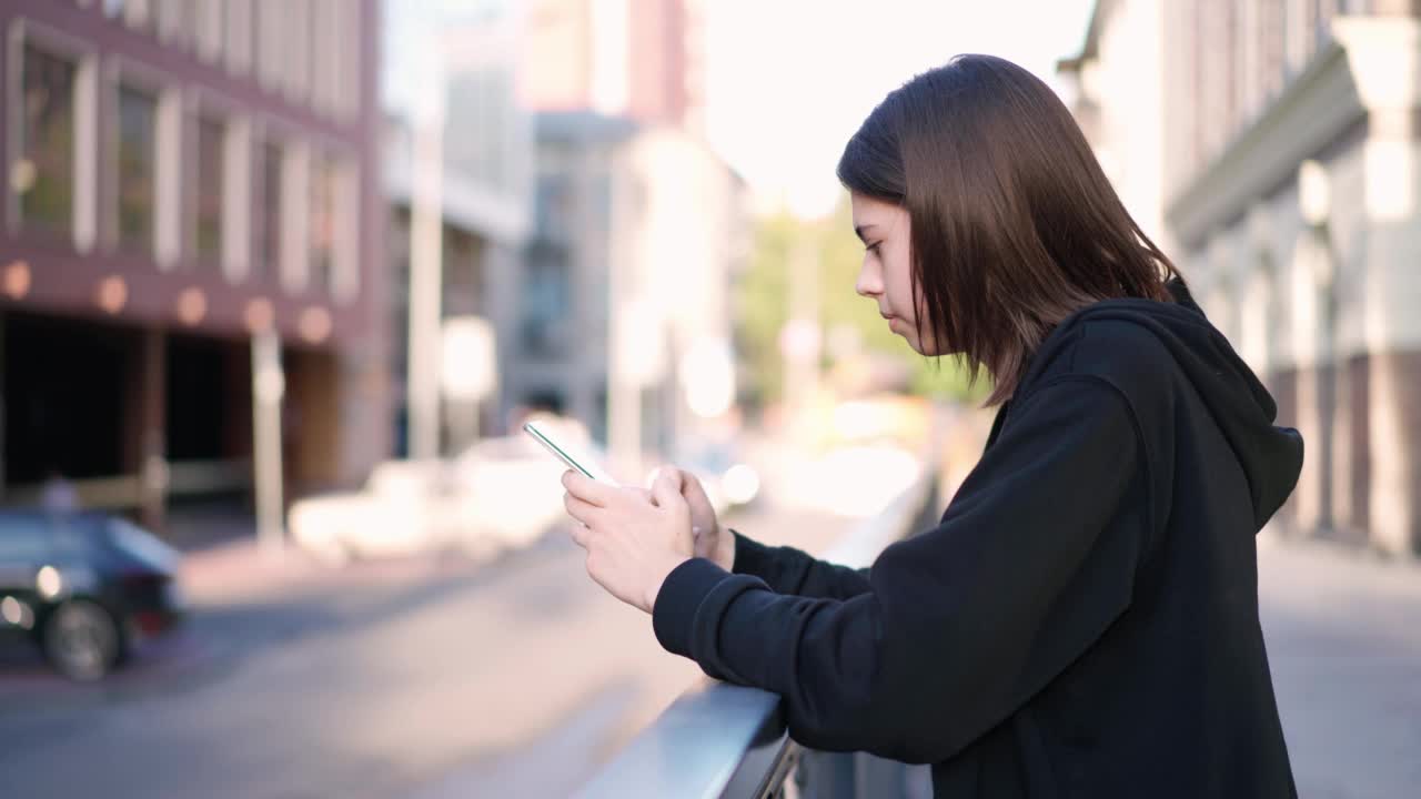 少年拿着手机在外面。女孩在户外打电话。视频素材