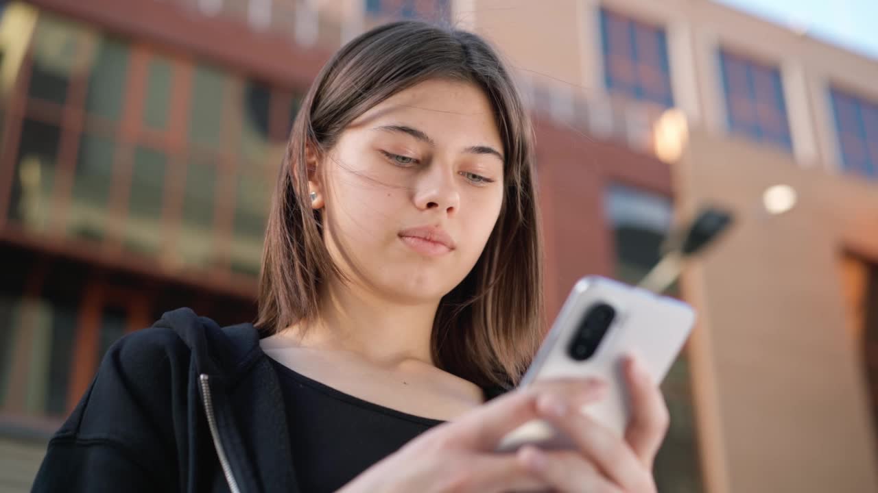 少年拿着手机在外面。女孩在户外打电话。视频素材