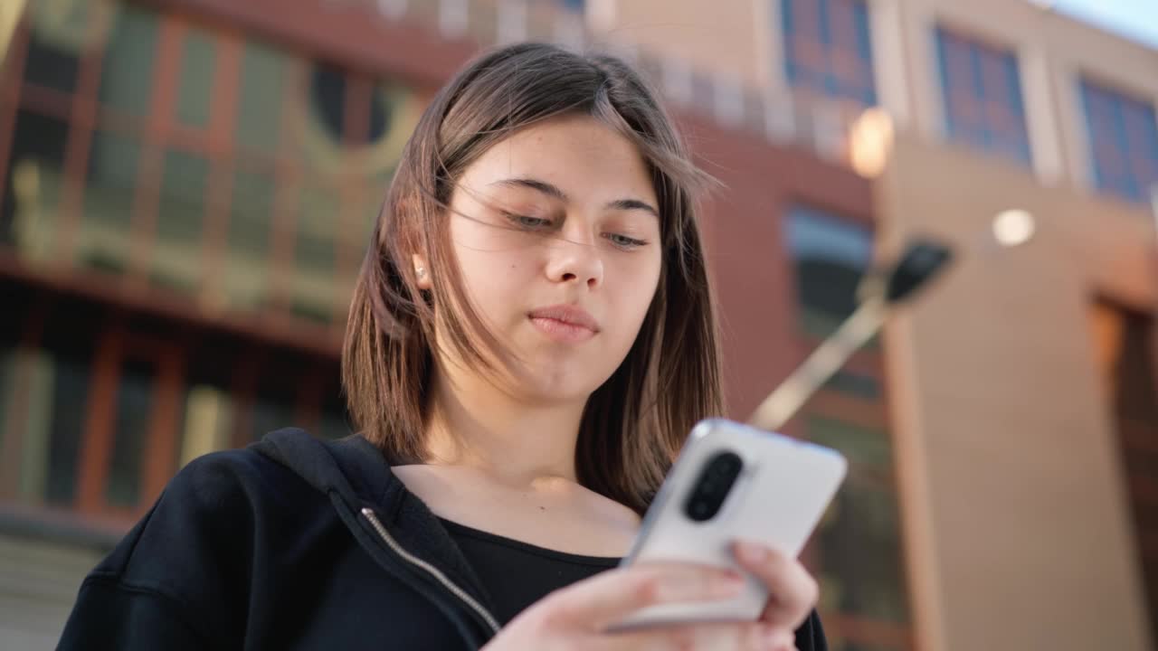 少年拿着手机在外面。女孩在户外打电话。视频素材