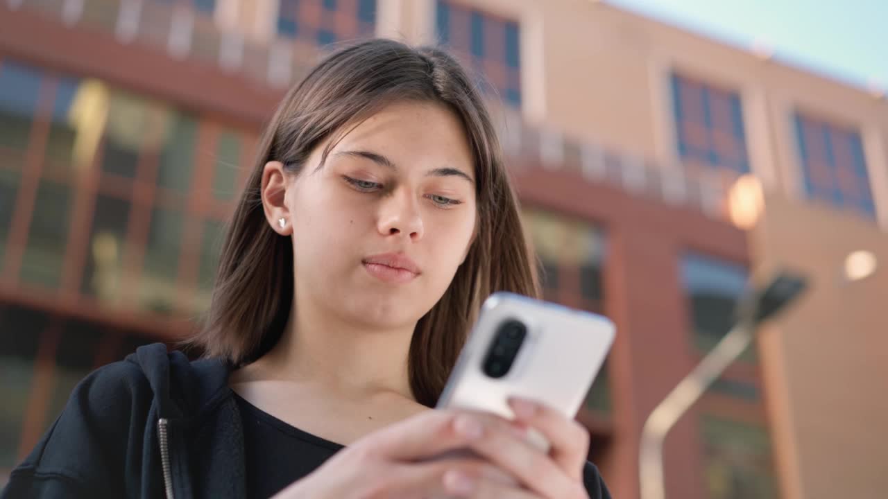 少年拿着手机在外面。女孩在户外打电话。视频素材