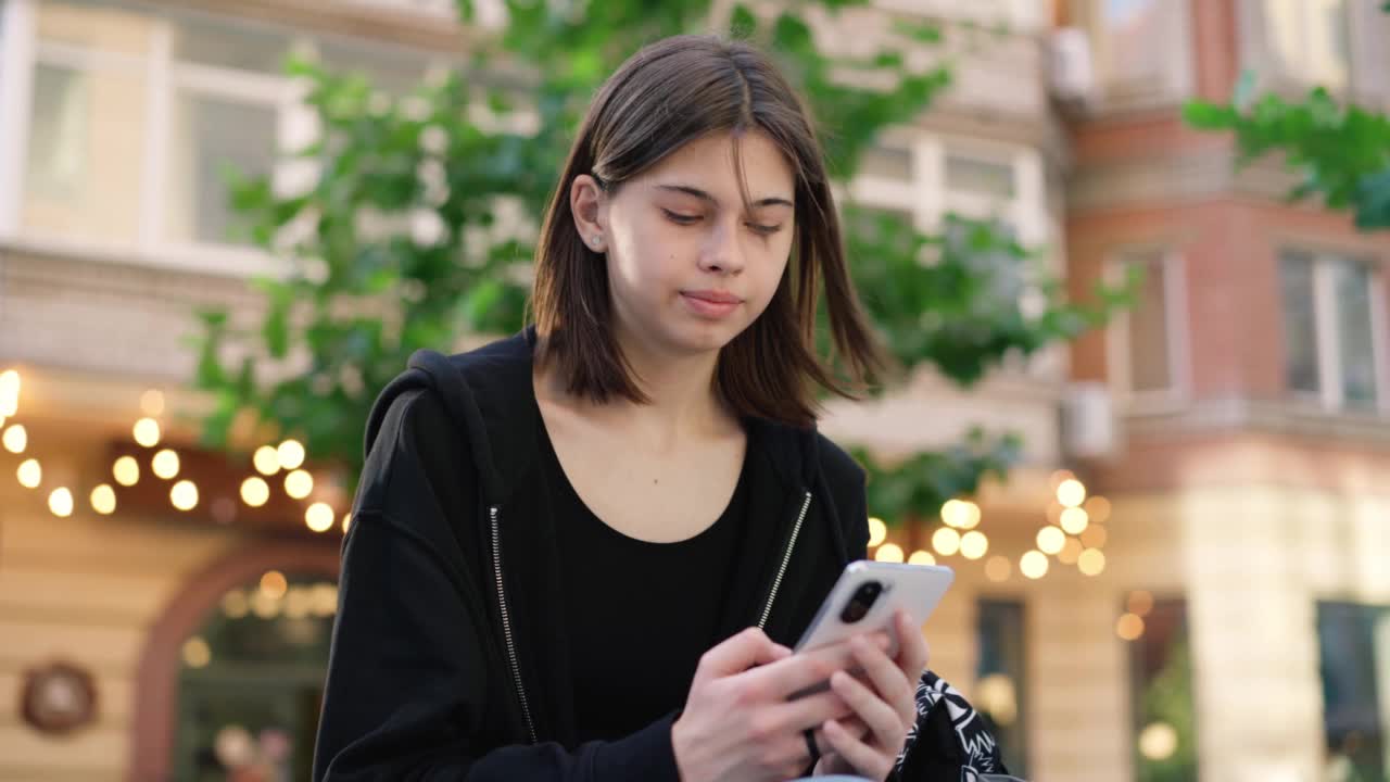 少年拿着手机在外面。女孩在户外打电话。视频素材